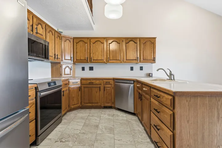 Kitchen featuring wood cabinetry, stainless steel appliances, light-toned countertops, and mosaic-style flooring