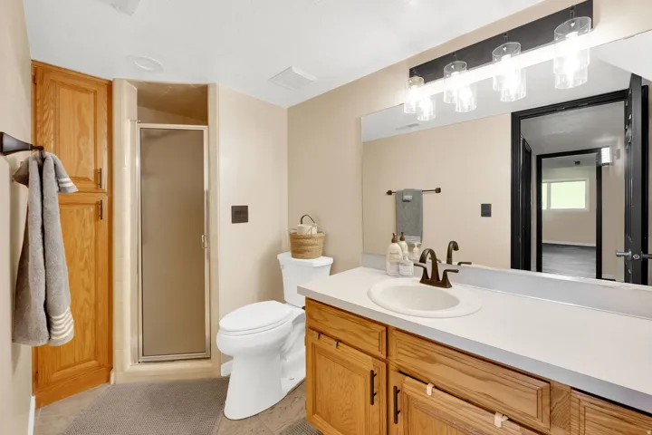 Bathroom featuring a single vanity with wood cabinetry, a white countertop, and a bronze faucet