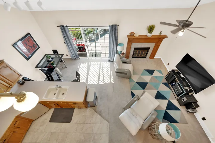 Open-concept living area featuring a vaulted ceiling and a fireplace with a wood mantle