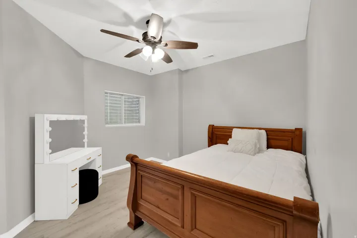 Spacious room with wood-finish flooring, a contemporary ceiling fan with integrated lighting, and a window with horizontal blinds