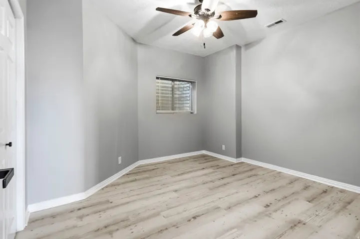 Light wood-finish flooring, recessed window with blinds, ceiling fan with light fixture, and neutral wall paint