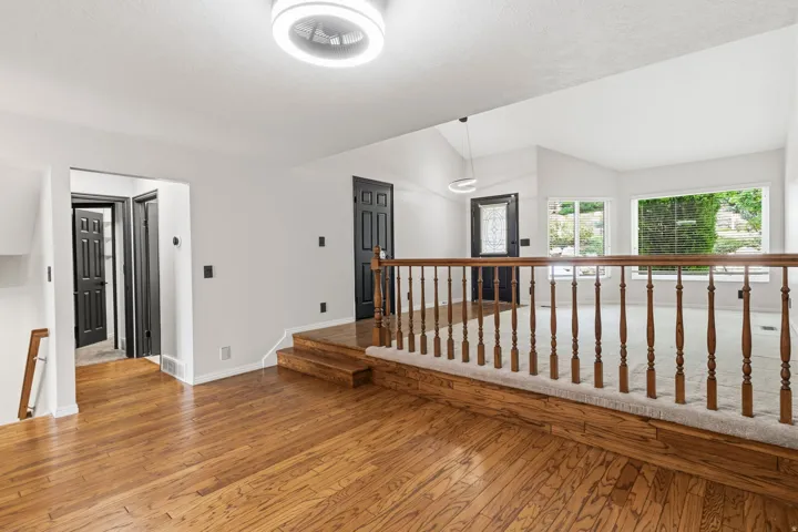 Hardwood flooring, painted interior doors, and a wood banister with carpeted stairs