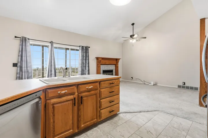 Kitchen island with a double basin sink, dishwasher, and wood cabinetry