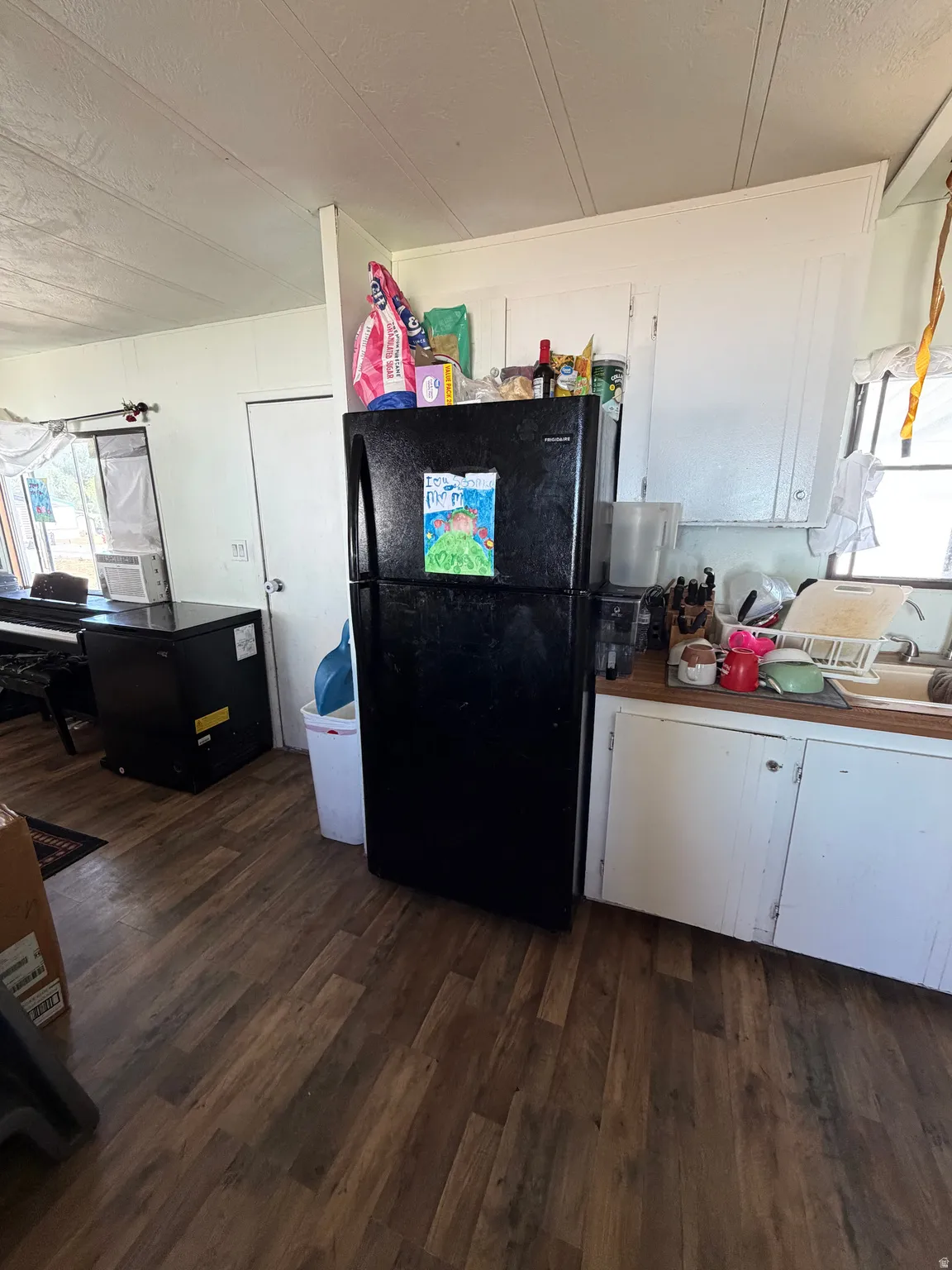 Kitchen area featuring wood-finish flooring, white cabinetry, a light-toned countertop, and a white interior door