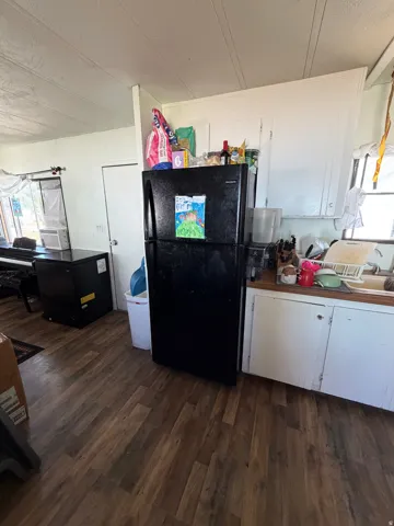 Kitchen area featuring wood-finish flooring, white cabinetry, a light-toned countertop, and a white interior door