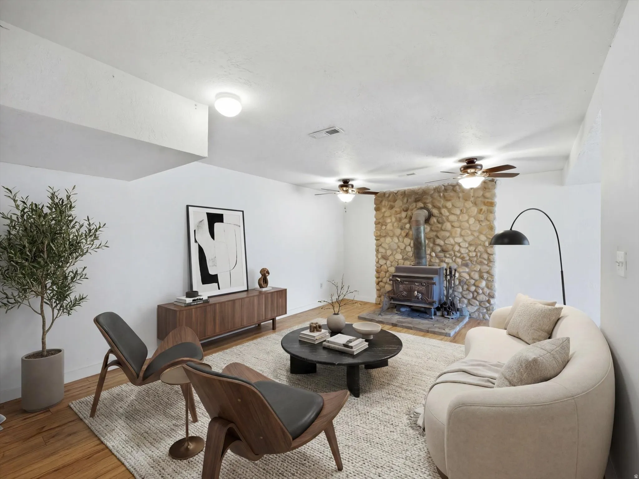 Virtually staged Living area featuring a stone accent wall with a wood-burning stove on a stone hearth