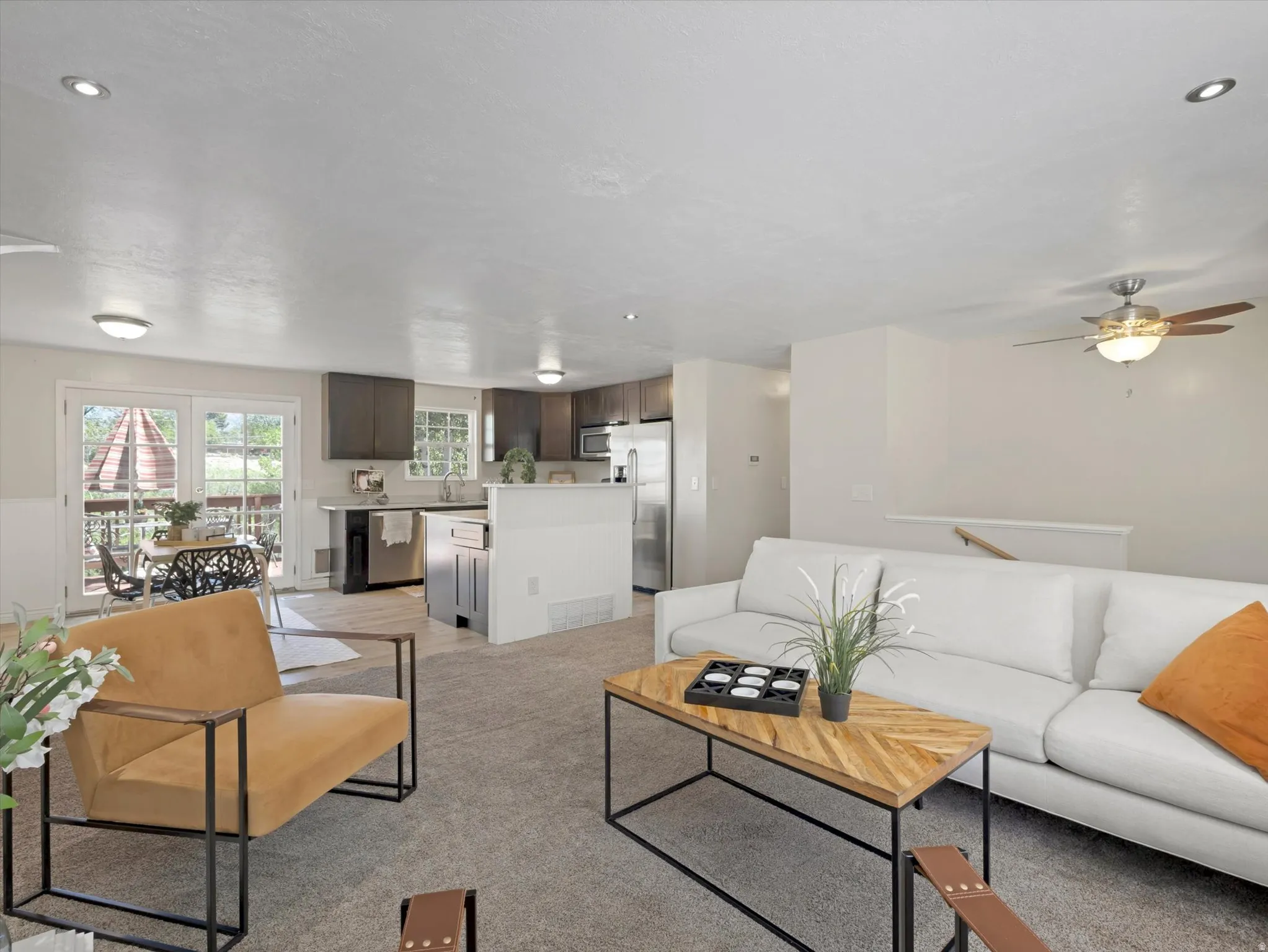 Open-concept living area featuring a kitchen with dark cabinetry, stainless steel appliances, and a breakfast bar