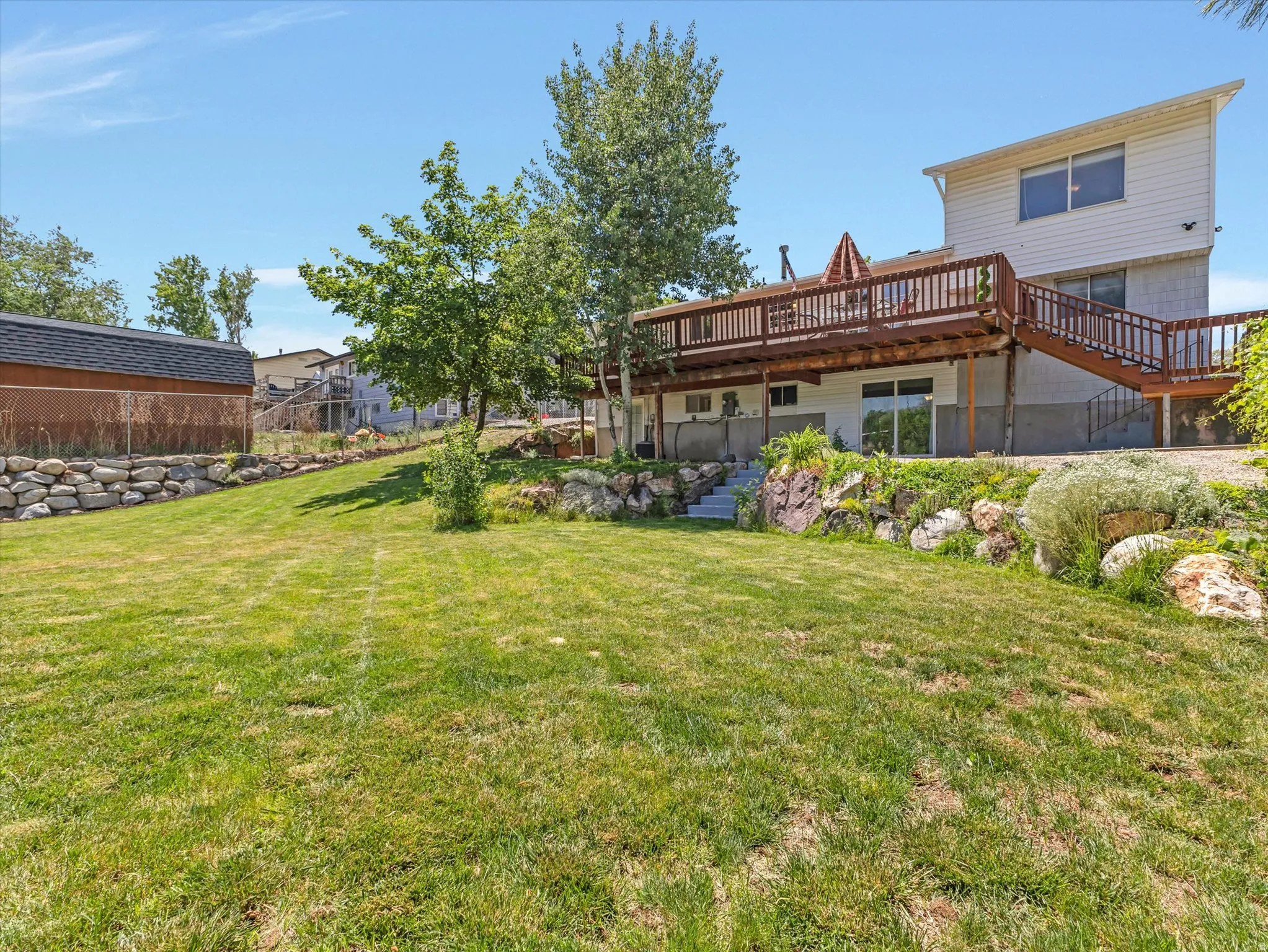 private back yard with a view Expansive backyard featuring a large green lawn, a multi-level deck with wooden railings, and a concrete patio