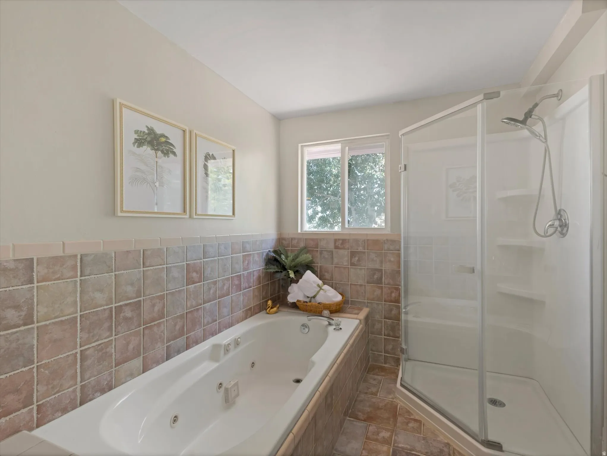 Soaking tub with integrated jets and tiled surround, accompanied by a glass-enclosed shower with multiple shelving units