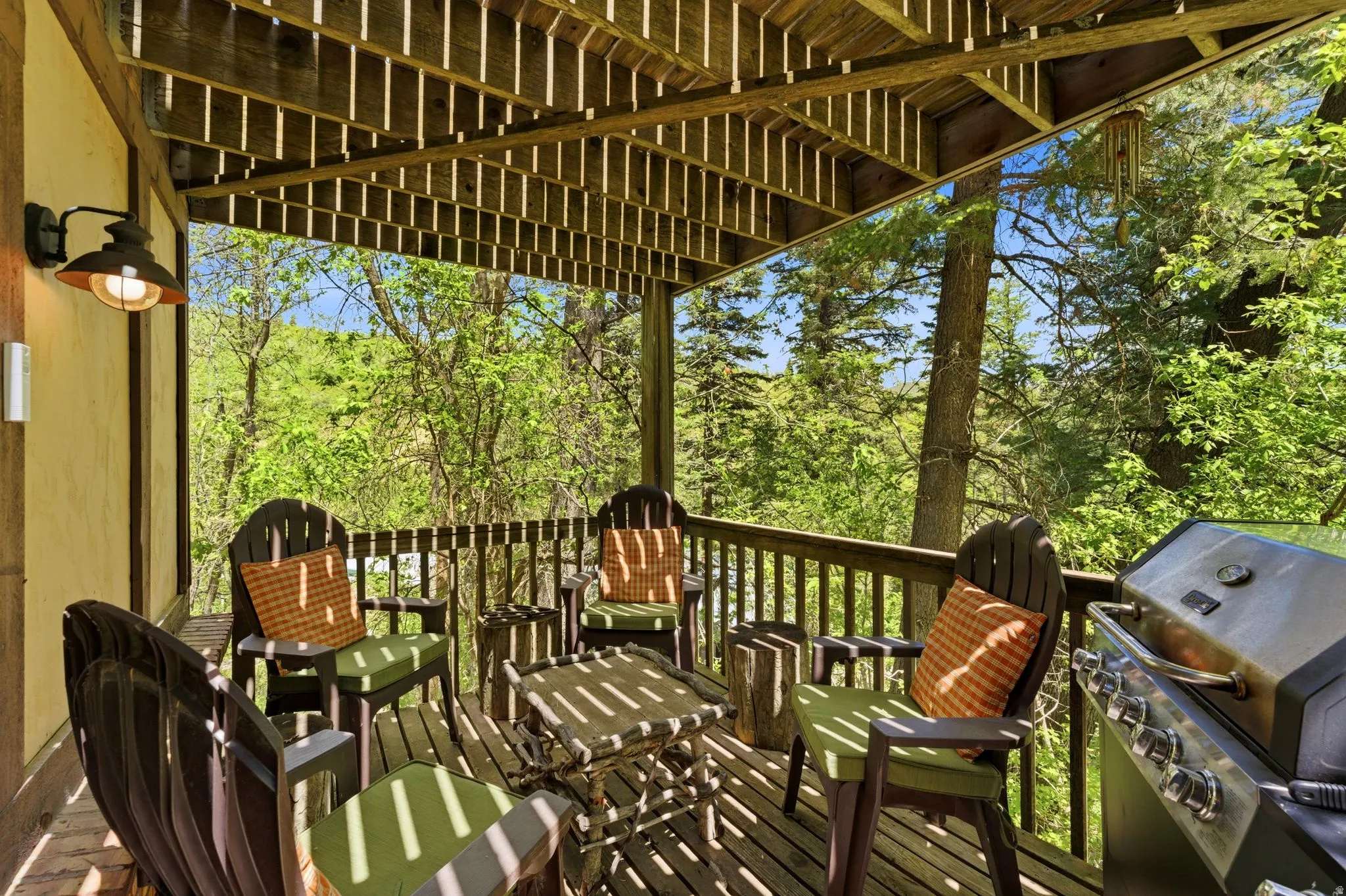 Expansive outdoor deck featuring wood flooring and railings, a slatted wood ceiling, and a wall-mounted exterior light fixture