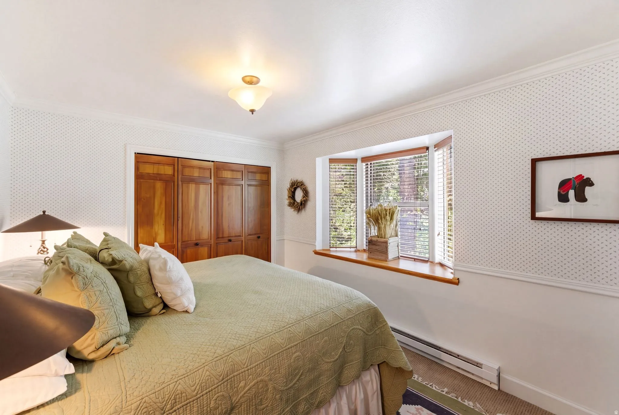 Bedroom featuring a bay window with wood blinds, wood-paneled closet doors, and crown molding