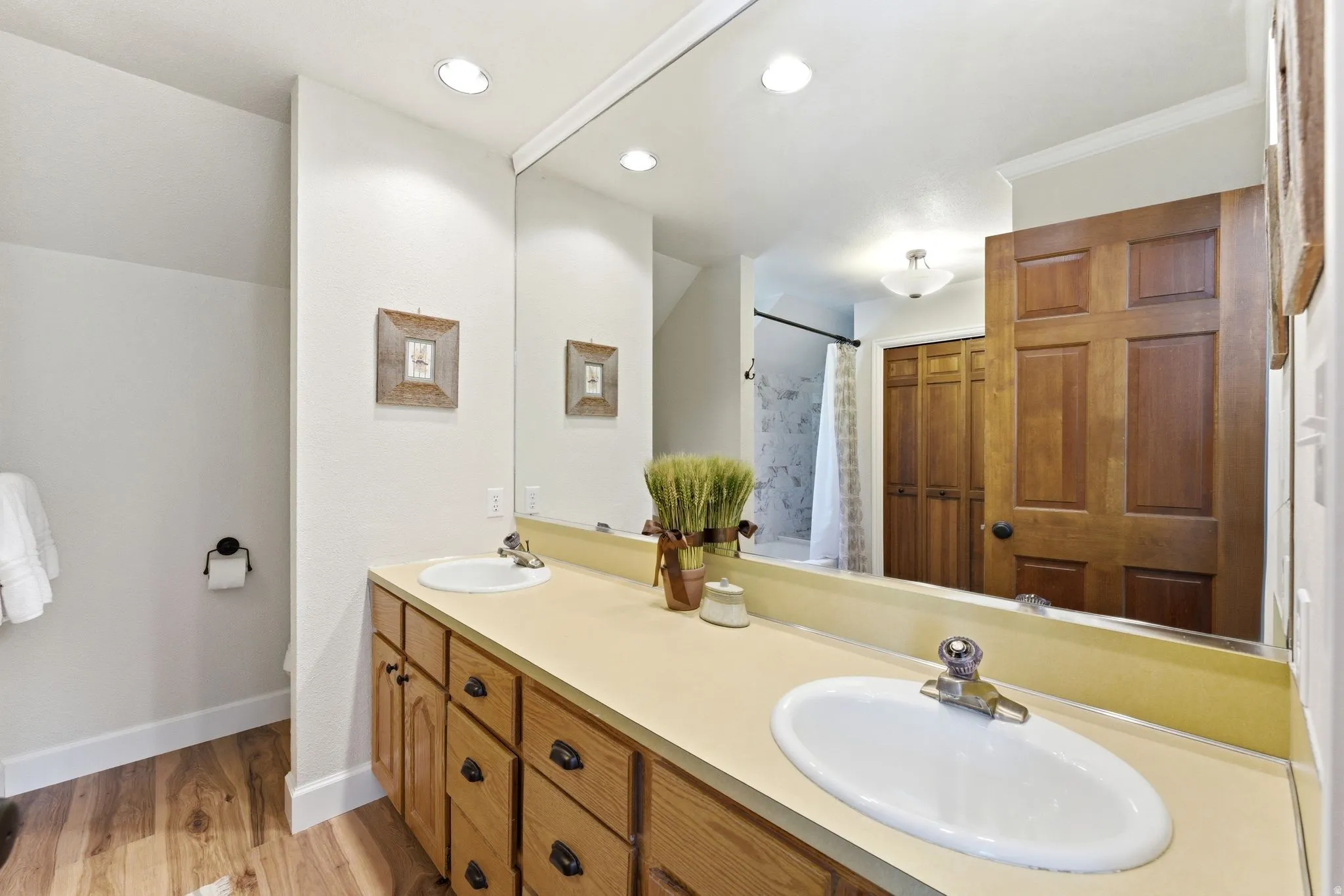 Bathroom featuring a double vanity with light wood cabinetry and a cream-colored countertop