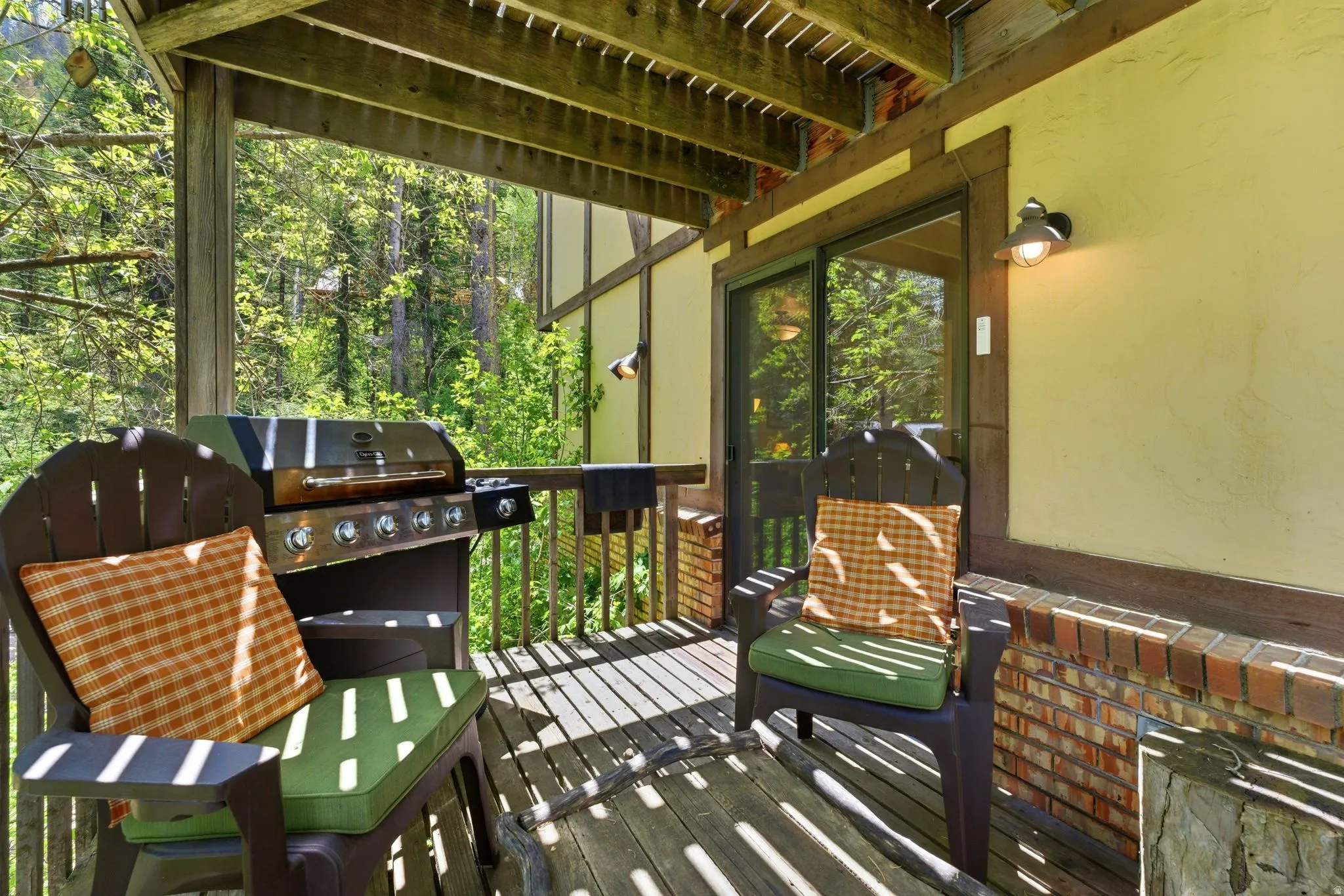 Outdoor deck with exposed wood beam ceiling, wood-finish flooring, and a sliding glass door entry