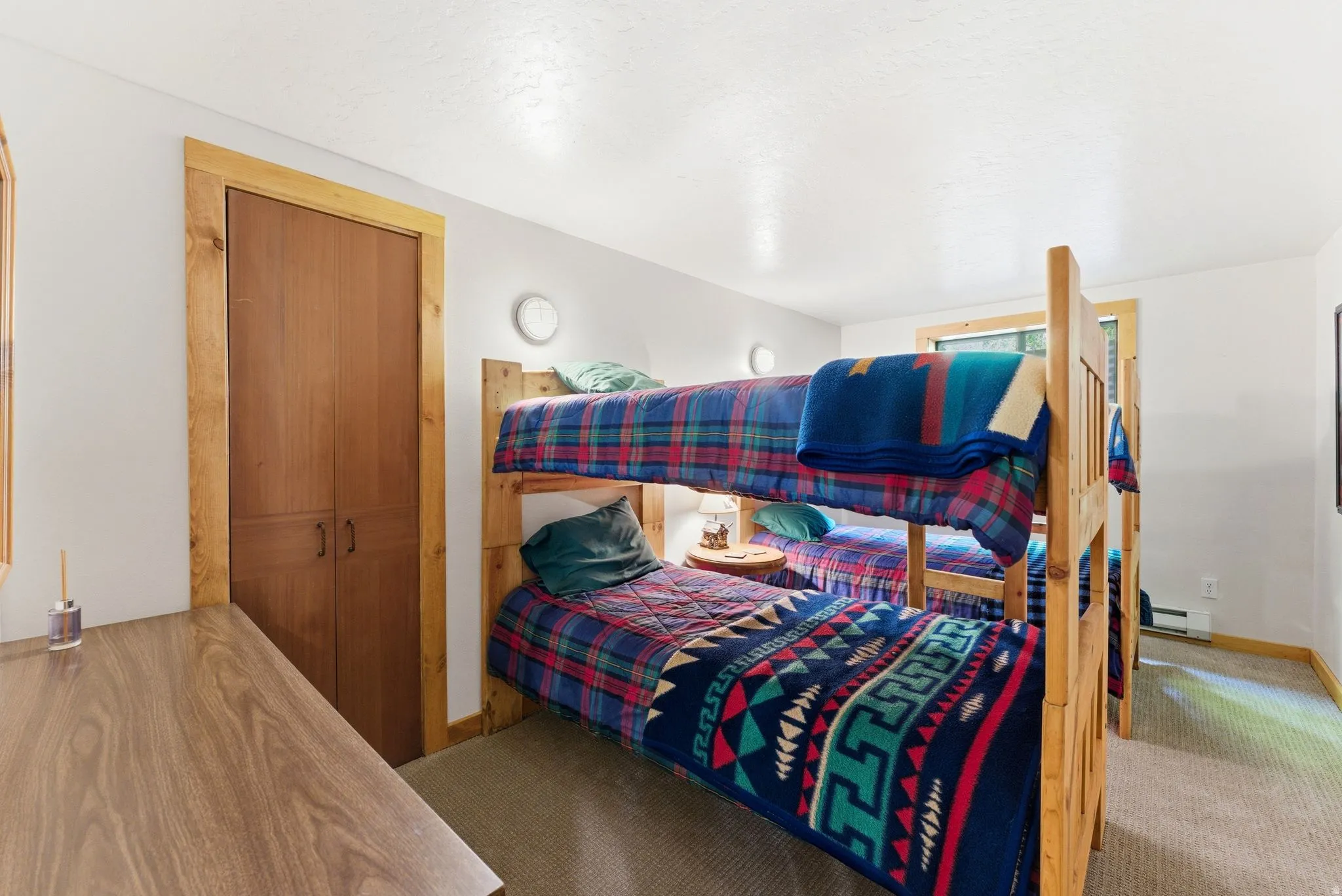 Room featuring two wooden bunk beds, light-toned carpeting, and a built-in closet with wood-finish doors