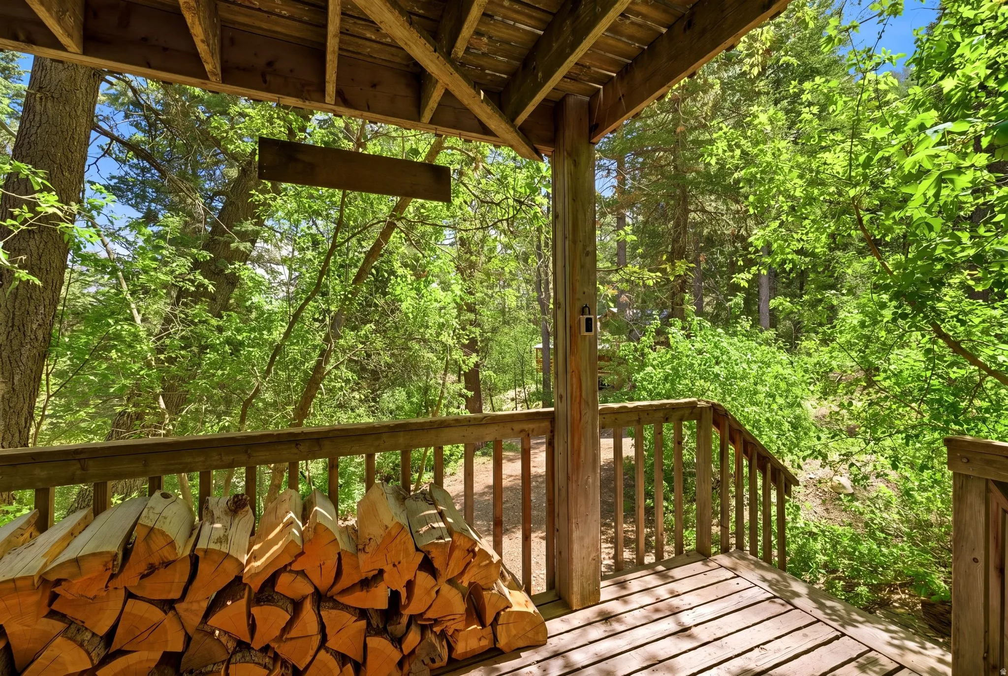 Spacious outdoor deck with natural wood railing and a wooded backdrop