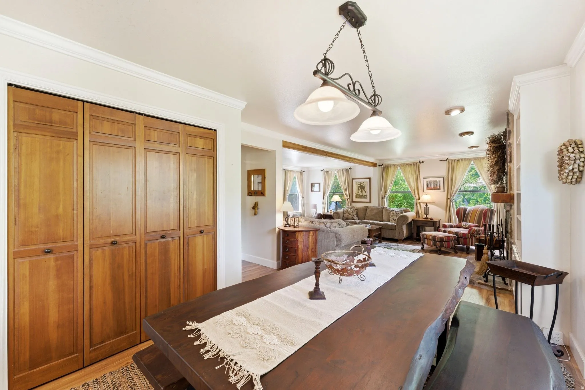 Dining area featuring a live-edge wood table, a decorative hanging light fixture, and wood-panel bifold closet doors