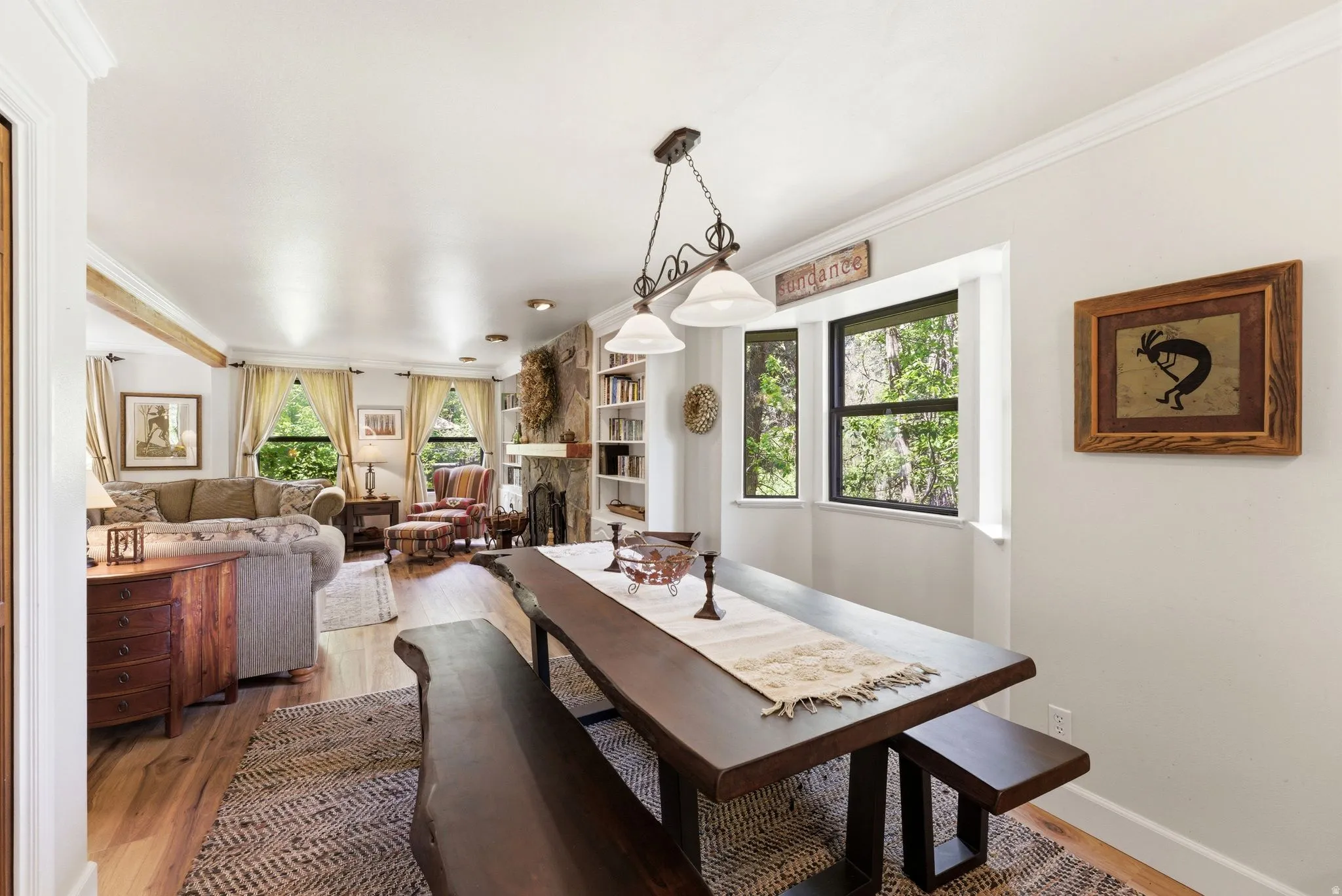 Dining area featuring a wood-finish table with matching benches, a decorative area rug, and a bay window