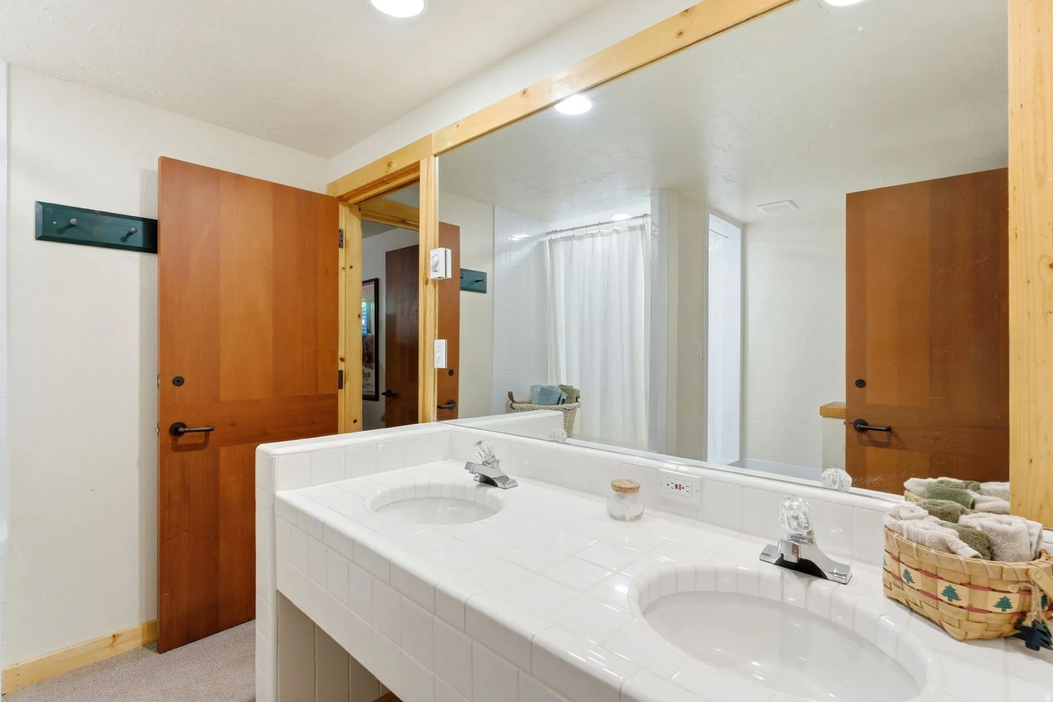 Double vanity featuring two integrated sinks with chrome faucets, a tile countertop, and a large wall-mounted mirror