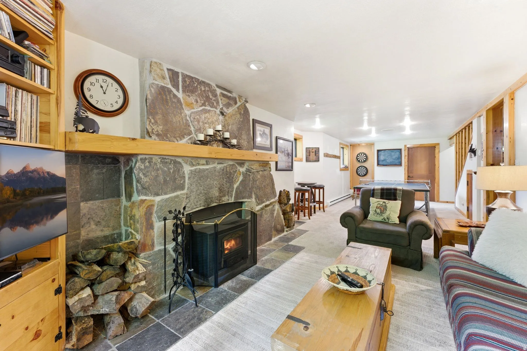 Stone fireplace with a wood mantle, integrated wood-burning insert, and slate tile hearth