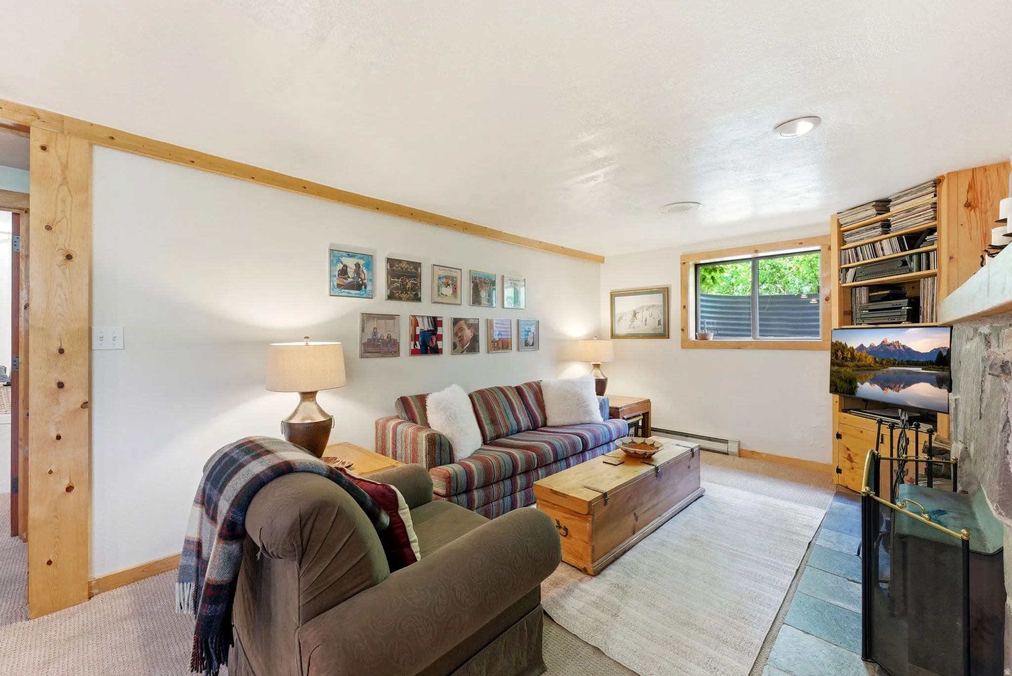 Living area featuring natural wood trim, a built-in bookshelf, recessed lighting, a stone fireplace surround, and a hearth with slate-look flooring