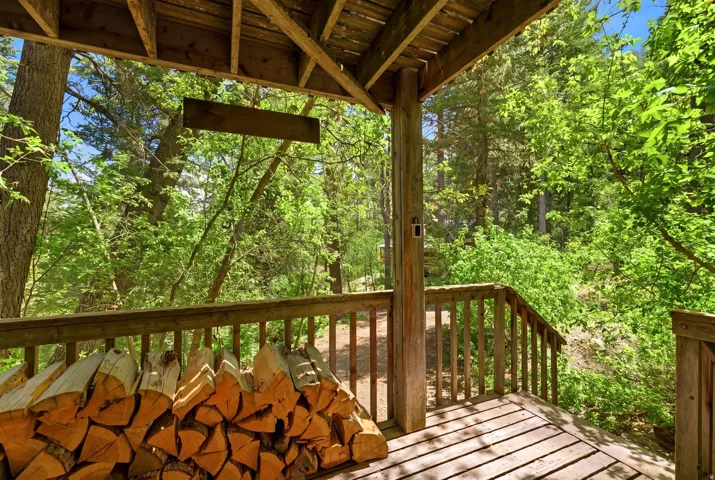 Spacious outdoor deck with natural wood railing and a wooded backdrop