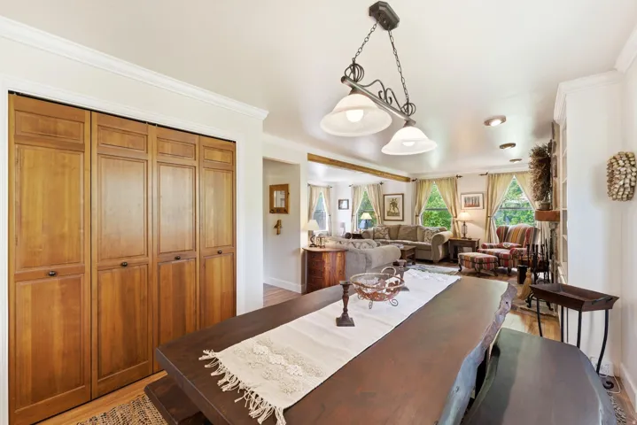 Dining area featuring a live-edge wood table, a decorative hanging light fixture, and wood-panel bifold closet doors