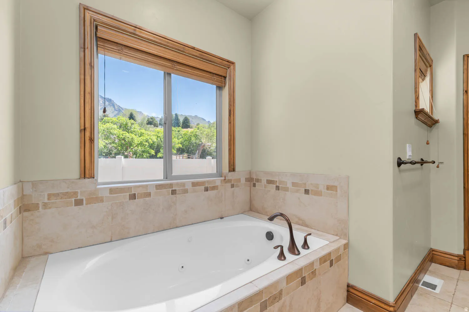 Built-in soaking tub featuring bronze fixtures and surrounding tilework with decorative accents