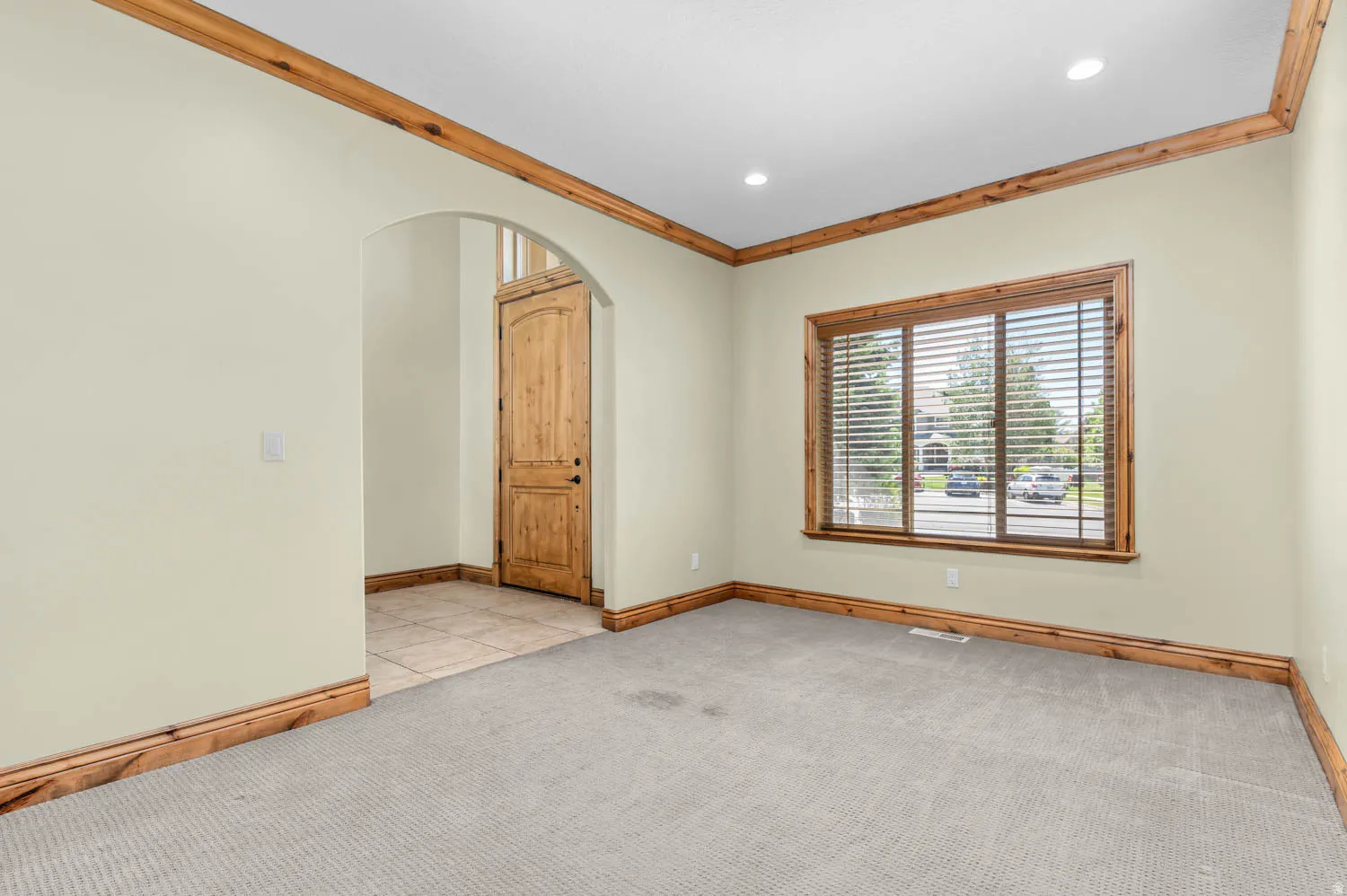 Spacious room featuring light-colored walls, wood-finish trim, and recessed ceiling lighting