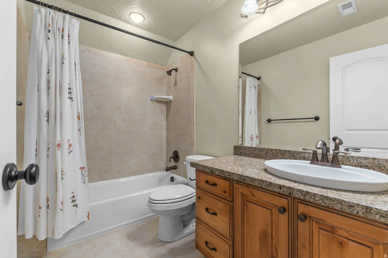 Bathroom featuring a wood-finish vanity with an oval vessel sink and a speckled countertop