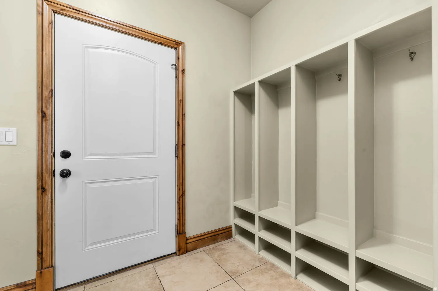 Built-in mudroom storage featuring individual cubbies with hooks and integrated shoe shelving