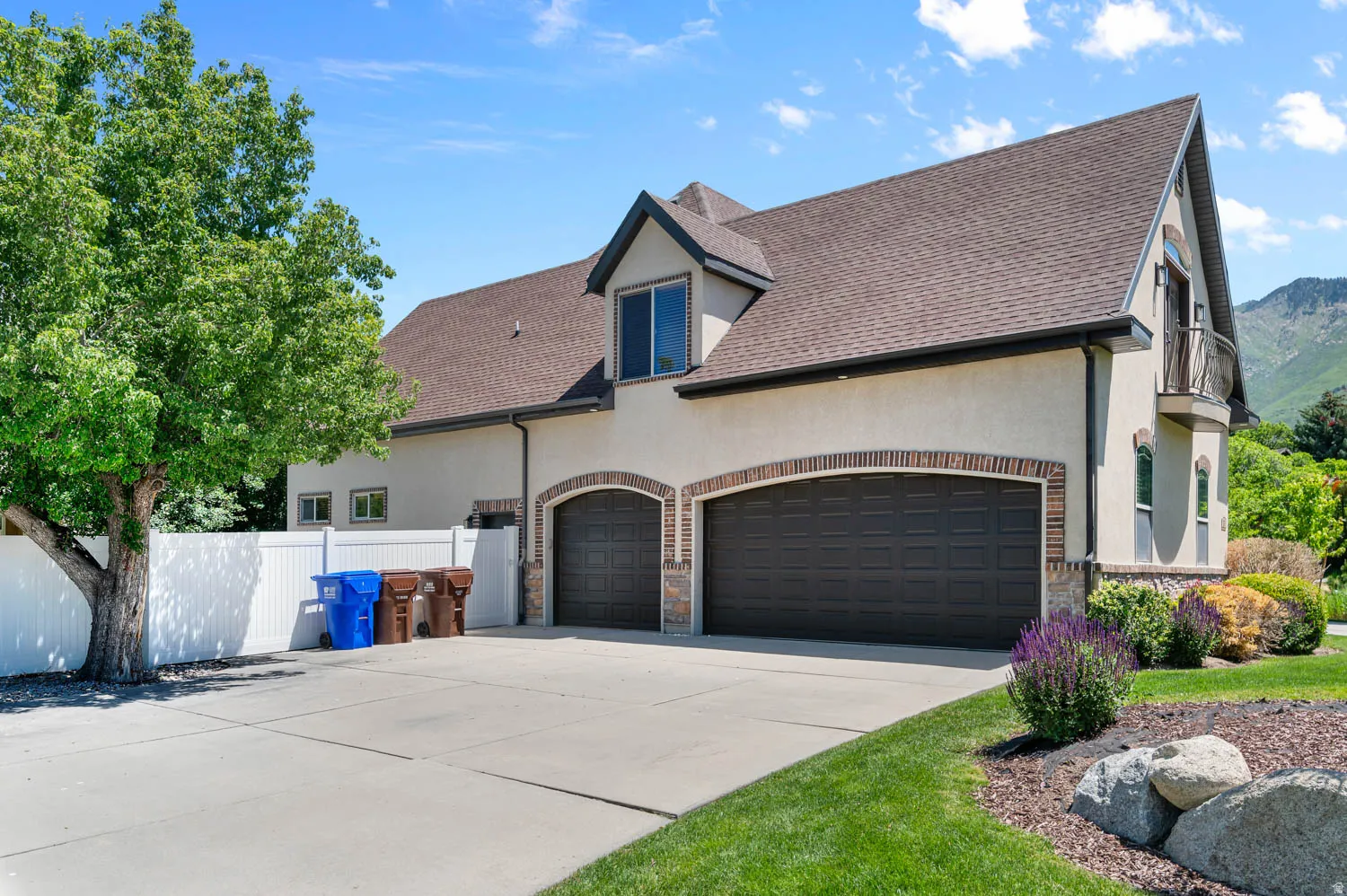 Stucco exterior featuring a two-car garage with arched brick detailing