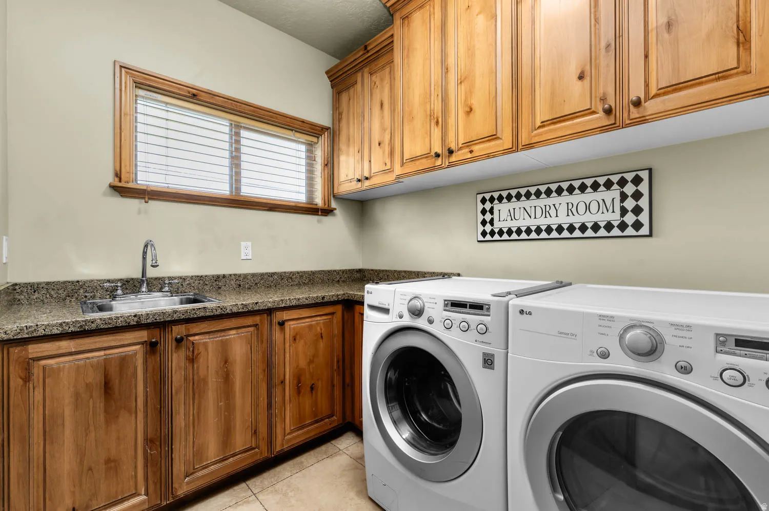 Dedicated laundry area featuring a utility sink, countertop space, and both upper and lower wood cabinetry