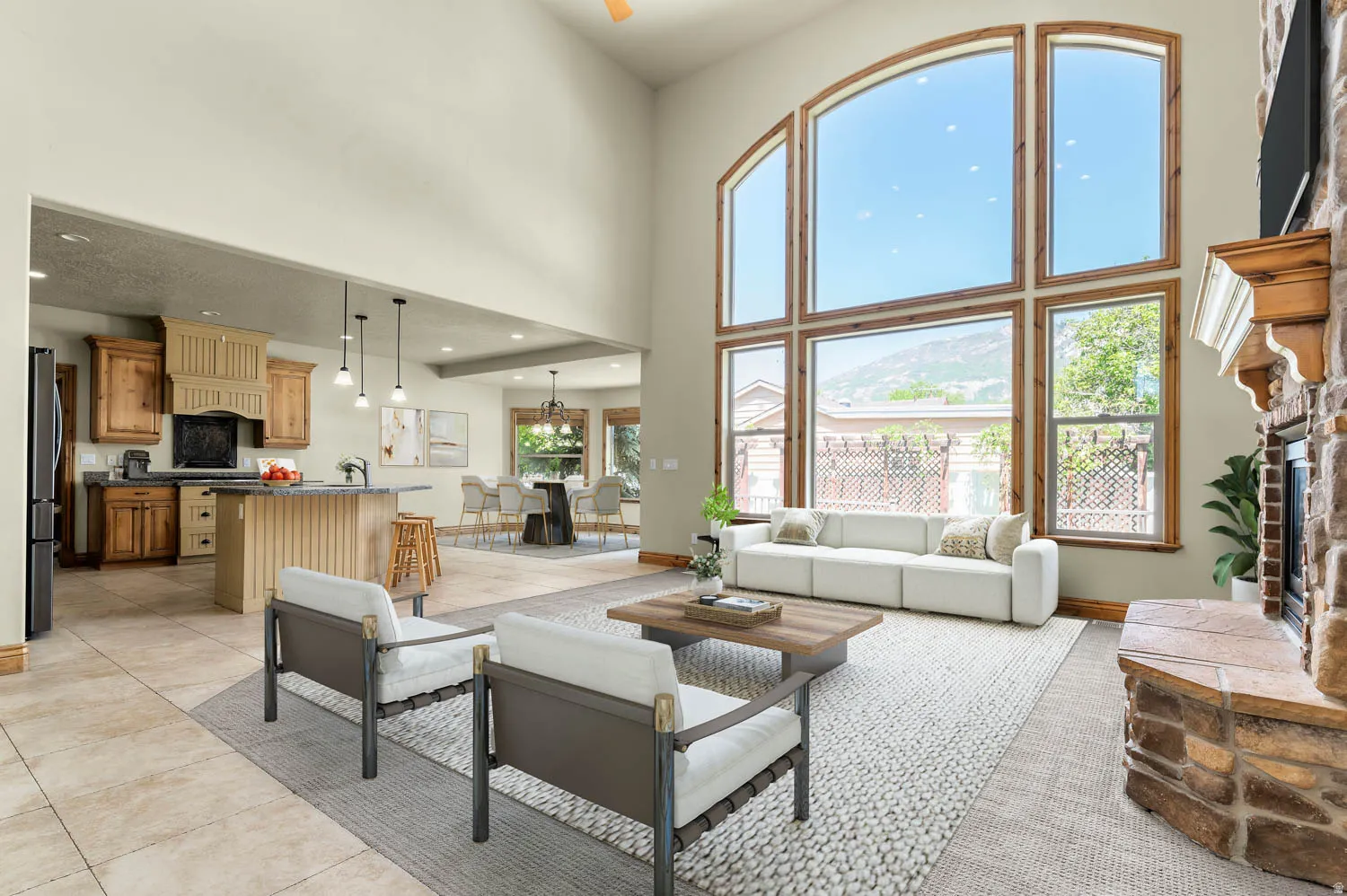 Great room featuring soaring ceilings, a stone-clad fireplace with a wood mantel, and expansive windows