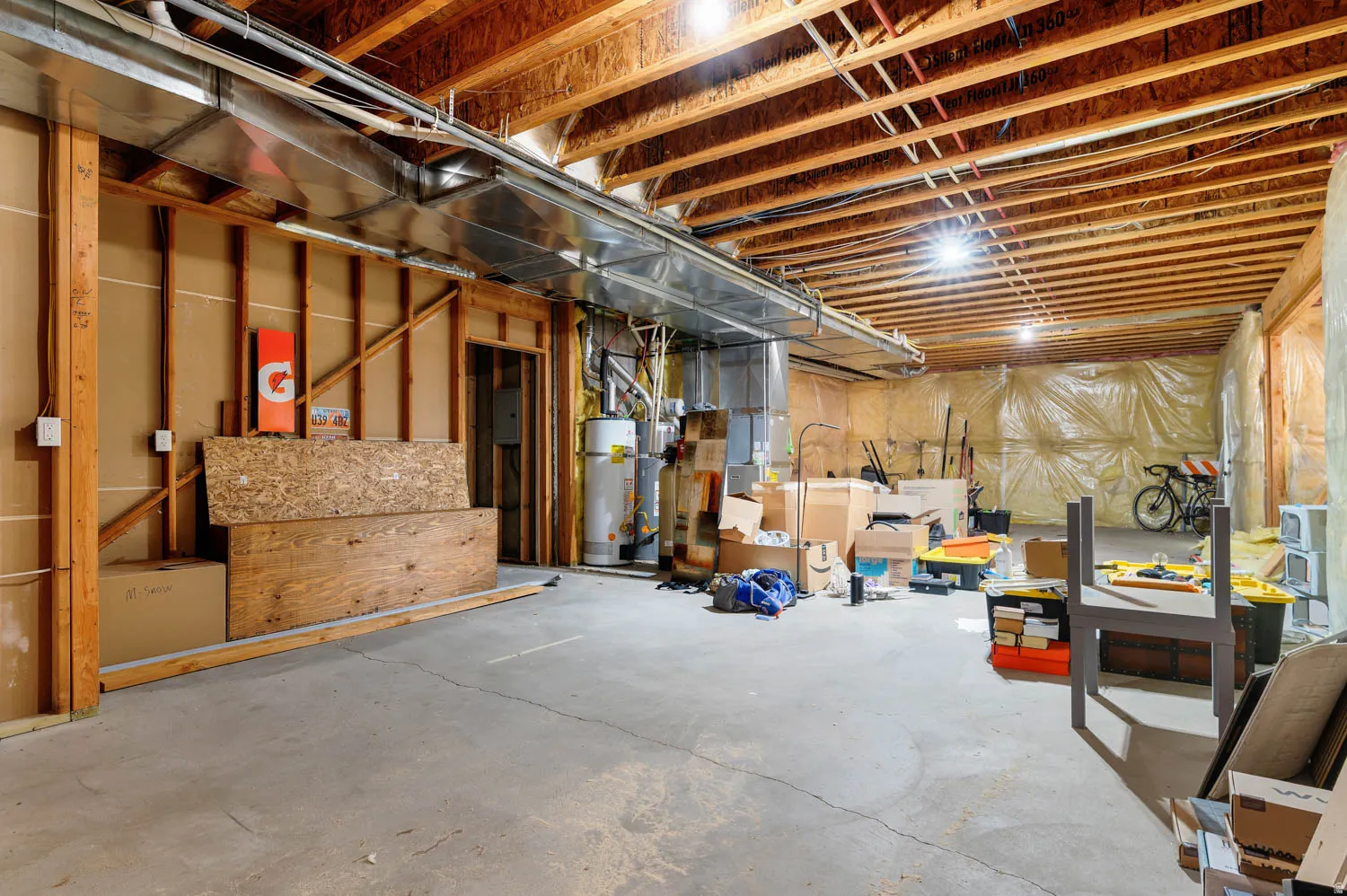 Unfinished basement featuring exposed wood joists, concrete flooring, and visible ductwork