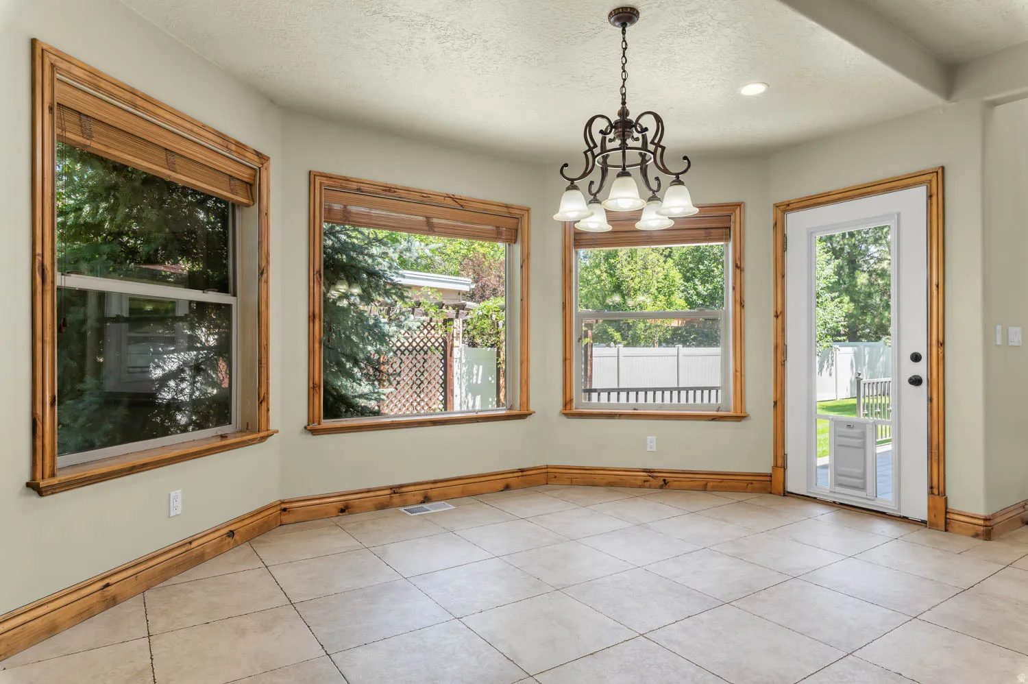 Dining area featuring light-toned tile flooring, substantial wood trim, and multiple large windows