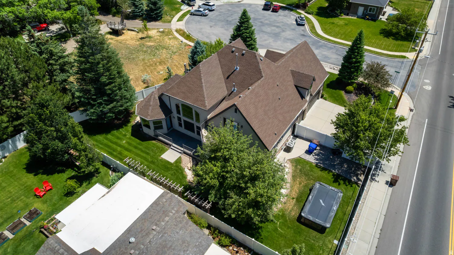 Spacious property featuring a multi-level roofline, extensive manicured lawn, mature trees, a concrete driveway, and a paved street