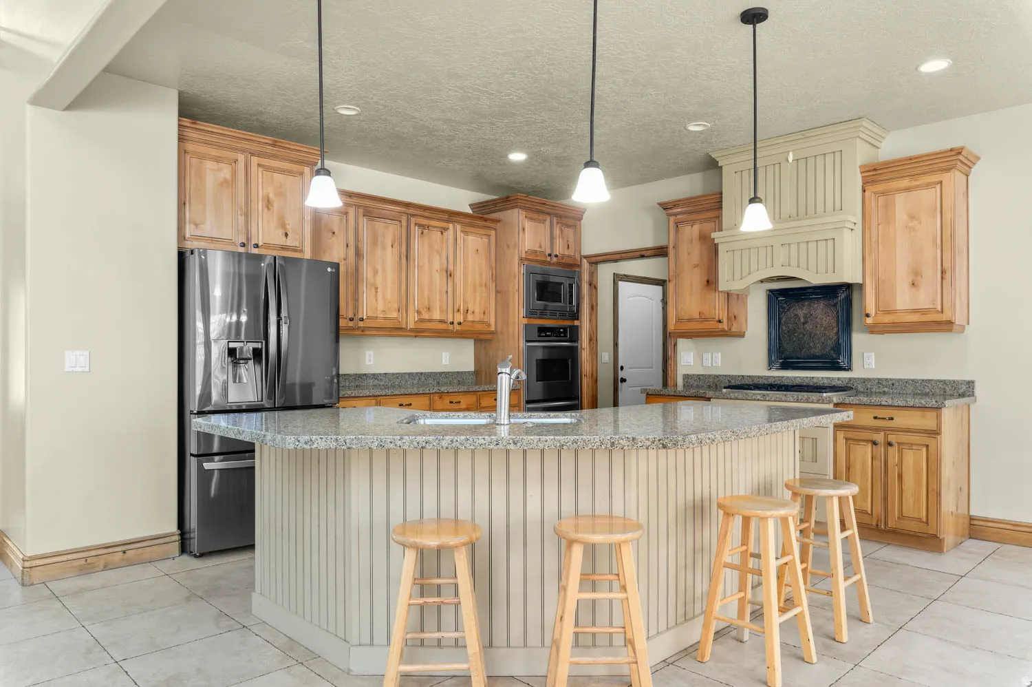Kitchen featuring a curved island with beadboard paneling, granite countertops, wood cabinetry, and stainless steel appliances