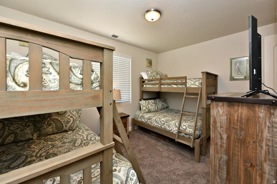 Carpeted room featuring two wood-finish bunk beds, a single window with blinds, and recessed lighting