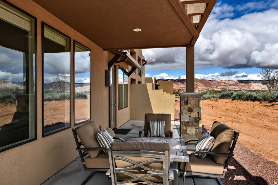 Covered patio with recessed lighting, stucco exterior, and a stone-clad support column