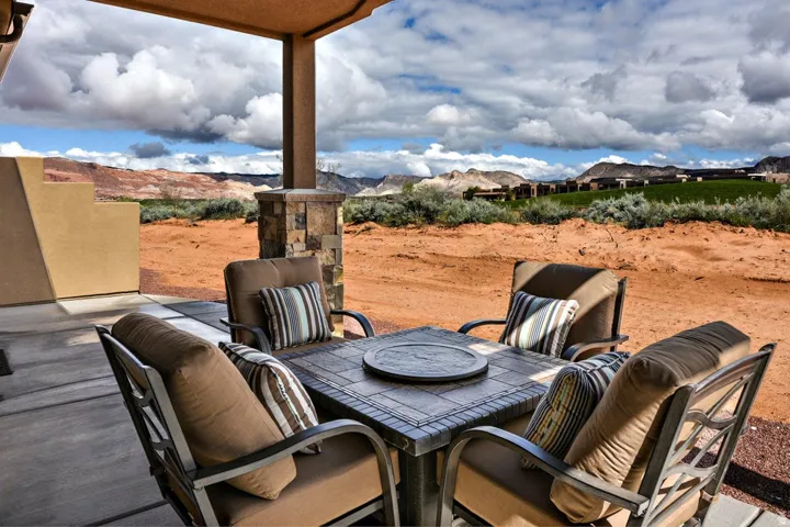 Covered patio with a concrete slab, a stone-clad support column, and stucco exterior walls