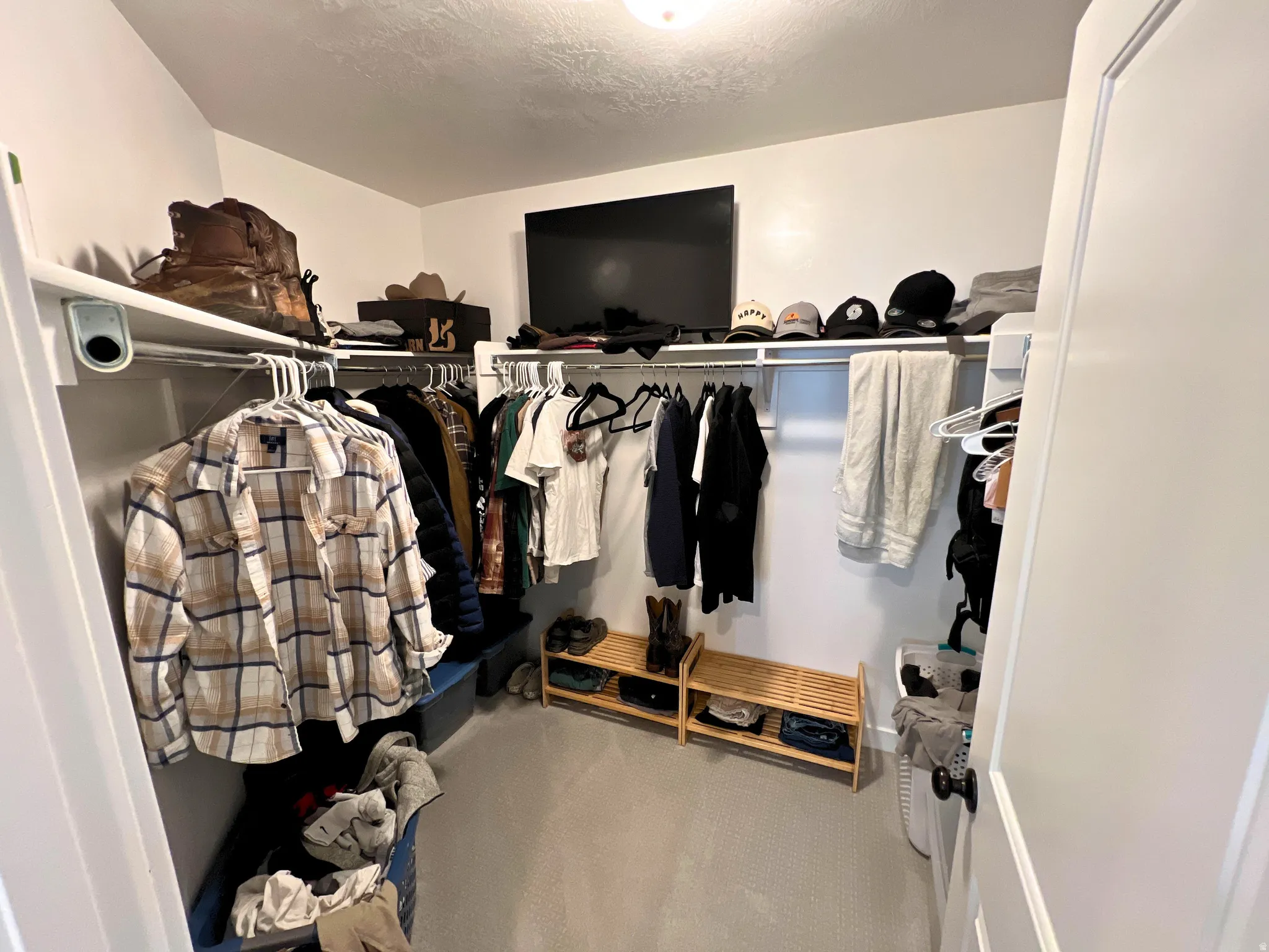 Walk-in closet featuring white walls, white wire shelving, and light gray carpet flooring