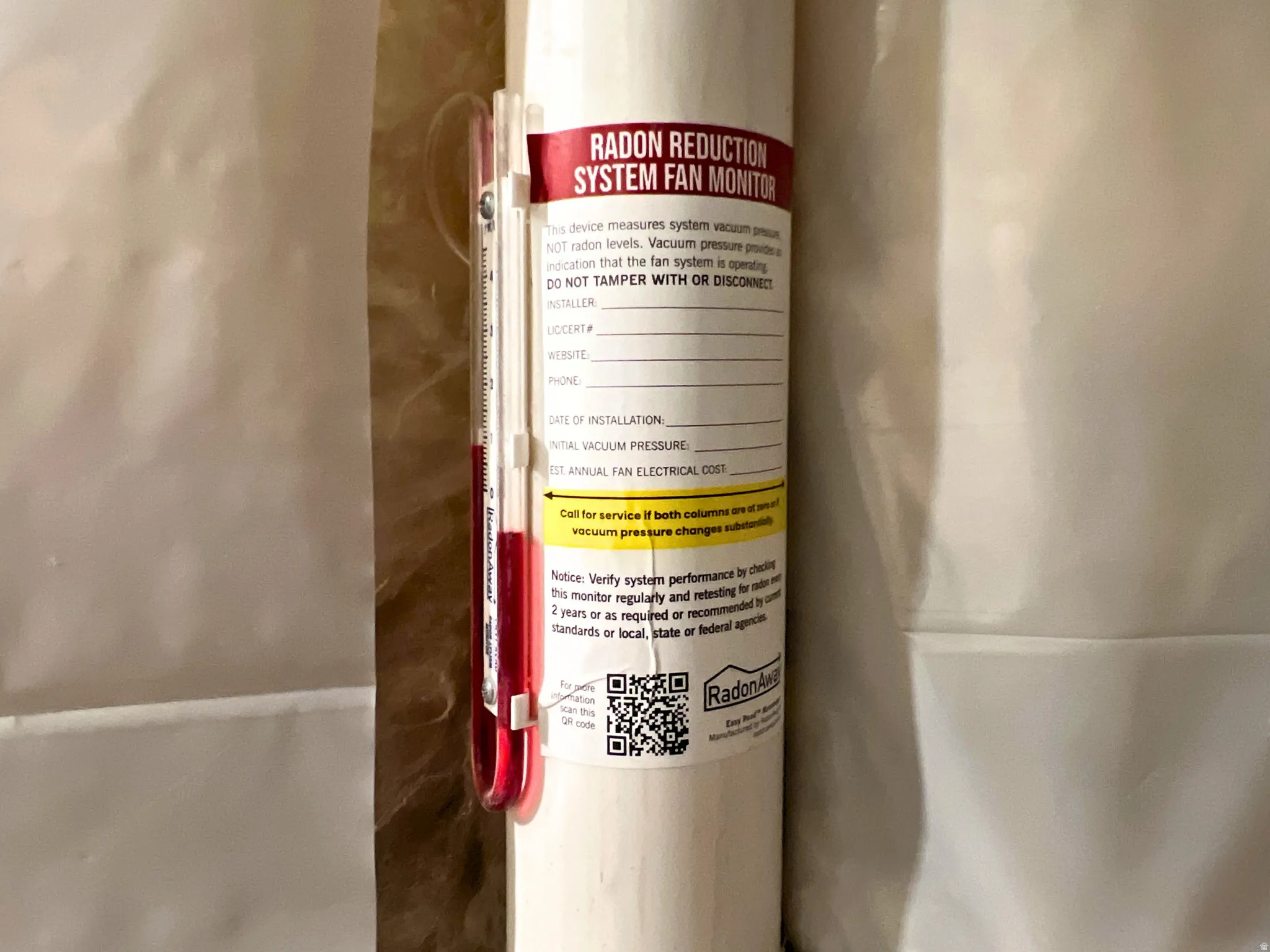 Radon reduction system fan monitor featuring a clear manometer tube