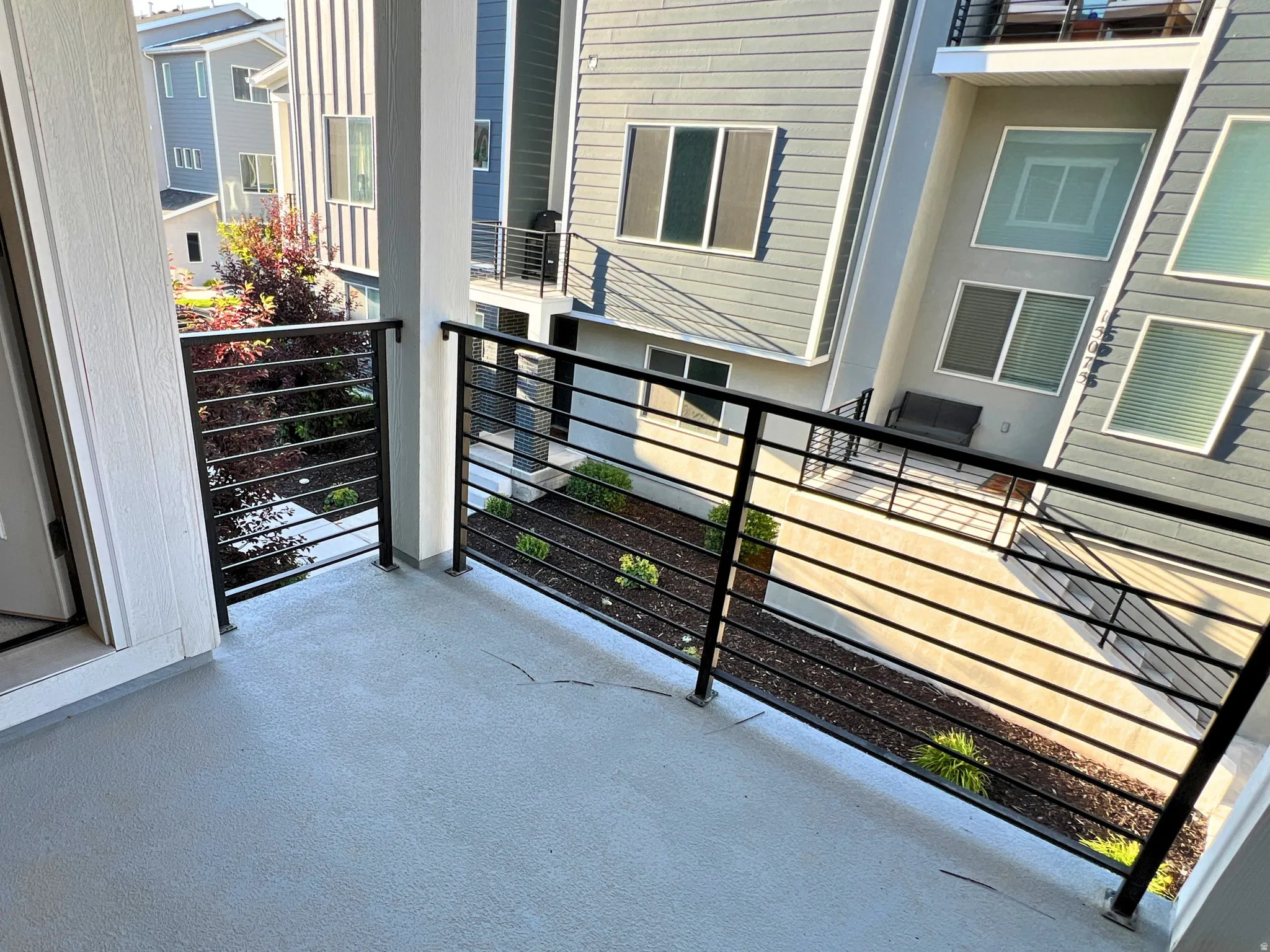 Private balcony featuring a textured concrete surface and contemporary horizontal metal railings