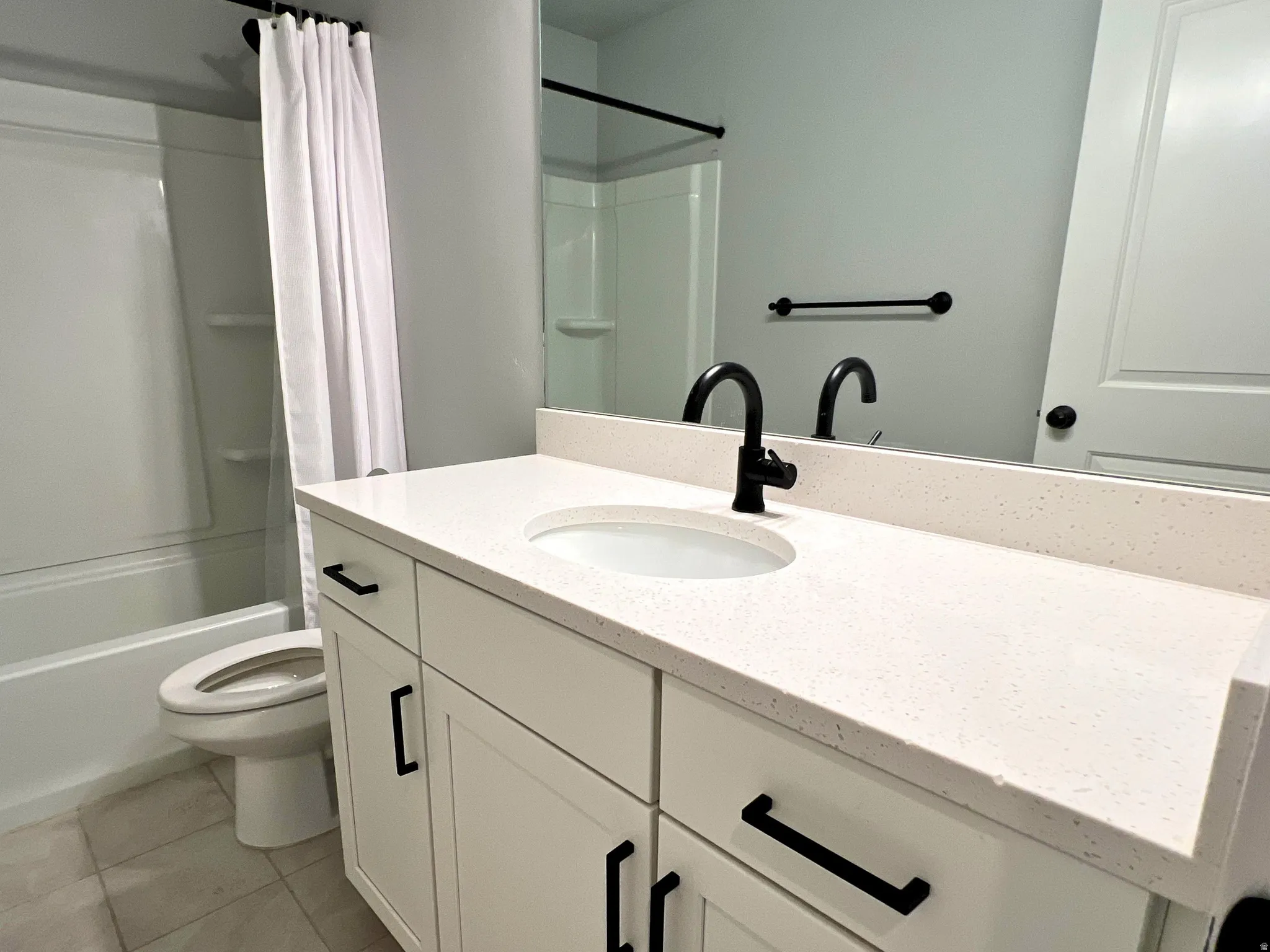 Bathroom featuring white vanity with matte black hardware, single undermount sink, and light-toned solid surface countertop