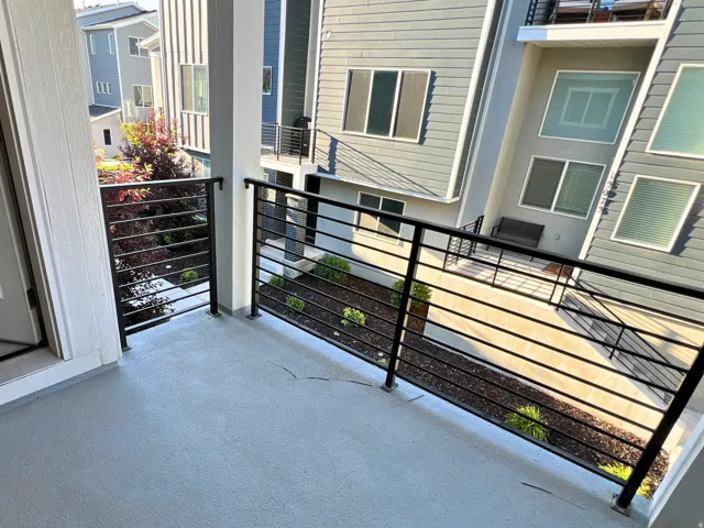 Private balcony featuring a textured concrete surface and contemporary horizontal metal railings