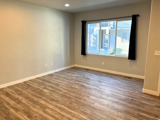 Spacious room featuring wood-finish flooring, neutral wall tones, and white baseboards