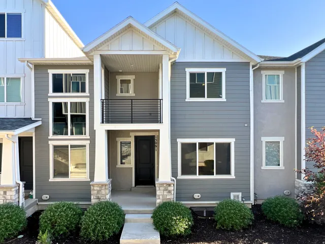 Modern townhome exterior featuring multi-level construction with a prominent entry porch and a second-story balcony