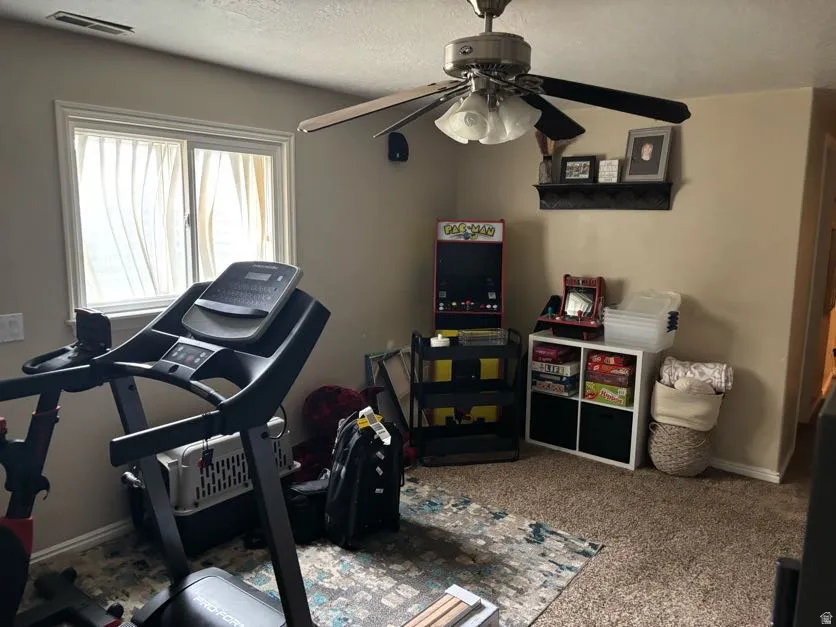 Carpeted family room featuring a ceiling fan with integrated lighting and a double window