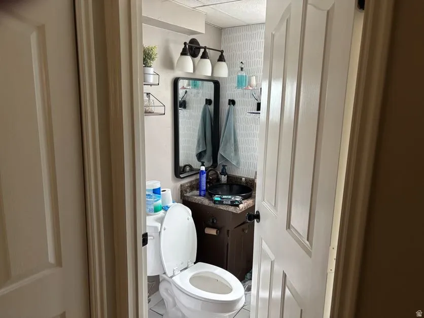 Bathroom featuring a dark wood-finish vanity with a black vessel sink, a granite-look countertop, and a contemporary black framed mirror