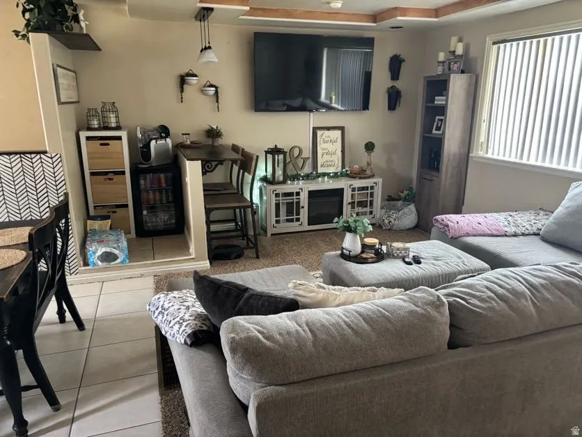 Living area featuring a tray ceiling treatment, wall-mounted television, and a dedicated beverage station